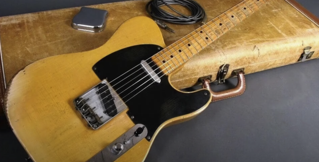 Photo of a wooden guitar accompanied by a wire and a guitar case