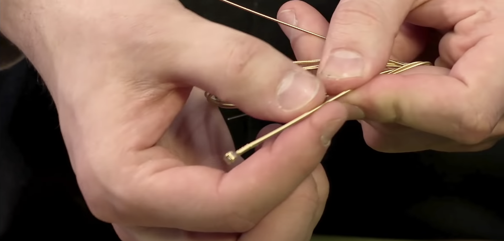 Hand holding a gold guitar string with both hands