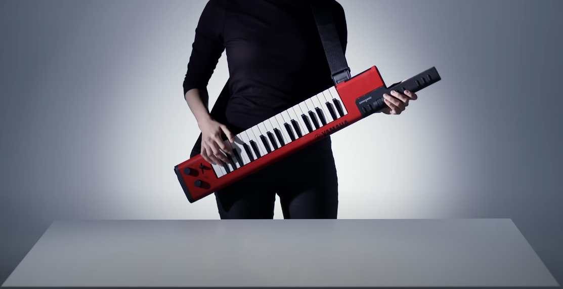 Photo of a girl dressed in black holding a red Yamaha SHS-500 Sonogenic Keytar