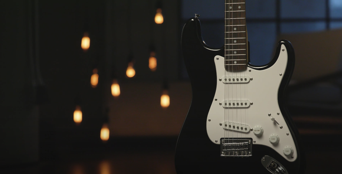 Photo of a black electric guitar standing upright, with blurred background lights shining